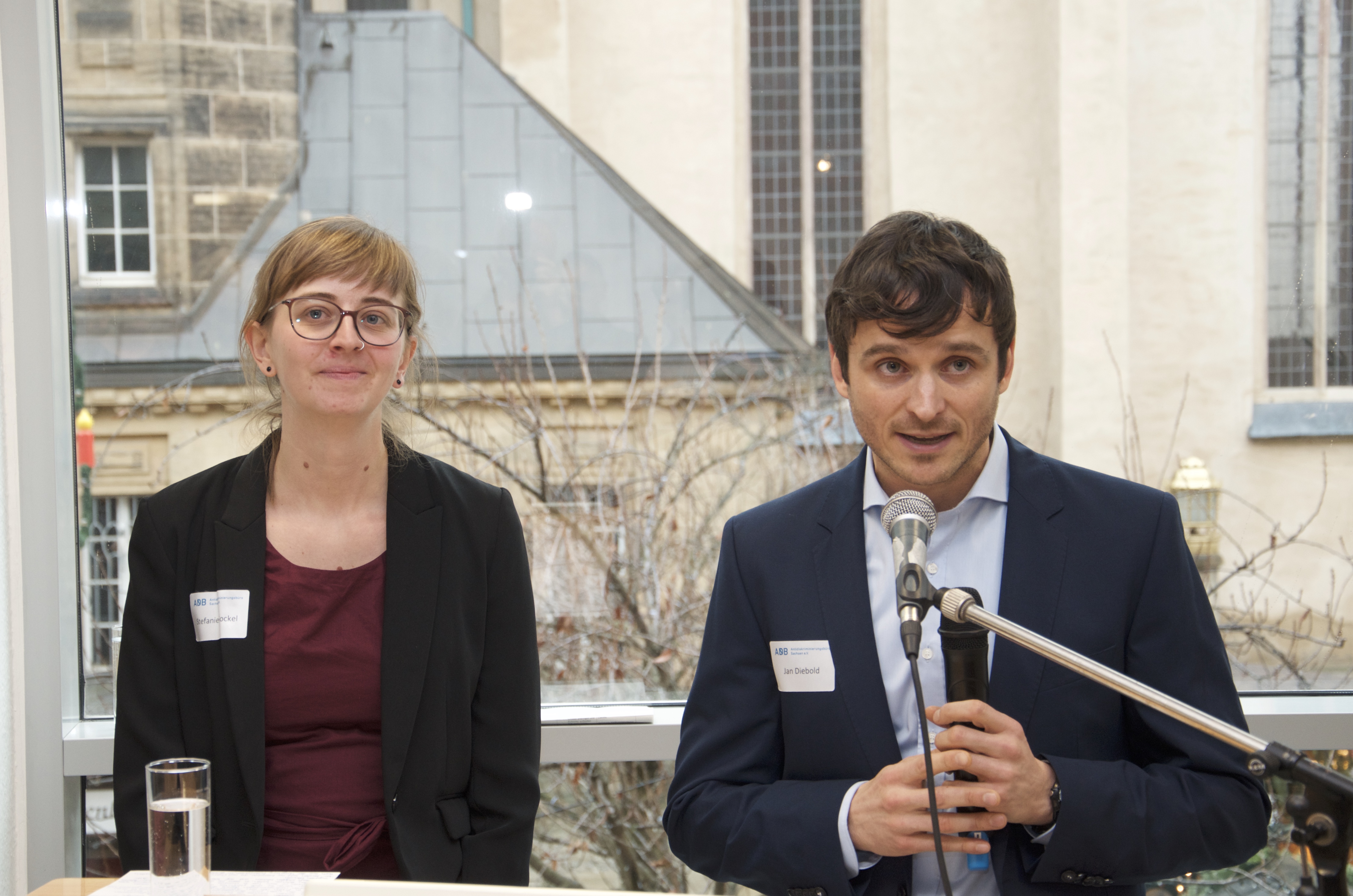 Stefanie Gockel, links, und Jan Diebold, rechts bei ihrer Begrüßung, im Hintergrund eine Fensterfront, dahinter der Jakobikirchplatz.