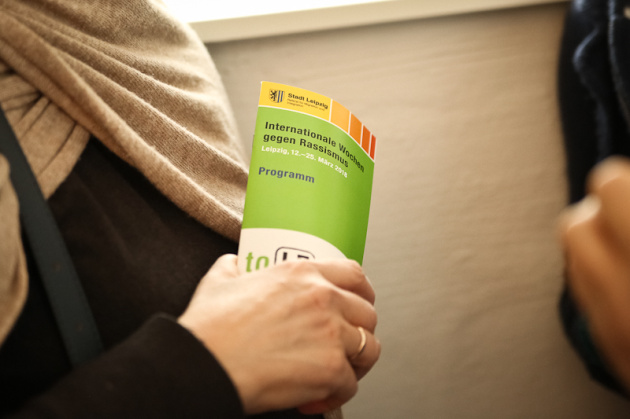 Eine Person hält ein Programmheft der Wochen gegen Rassismus in der Hand