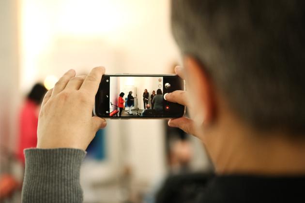 Ein Mensch filmt mit seinem Smartphone eine Pressekonferenz