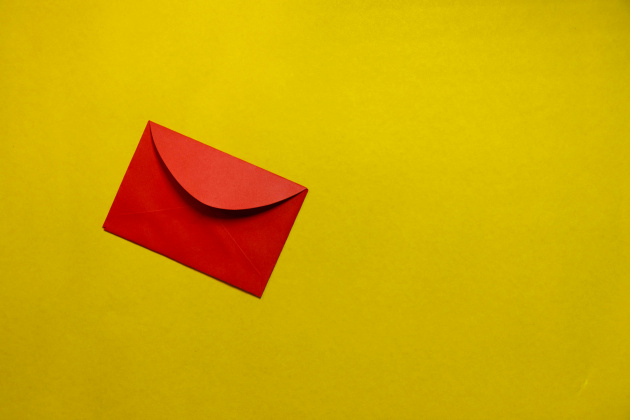 Ein knallroter Briefumschlag auf gelbem Untergrund